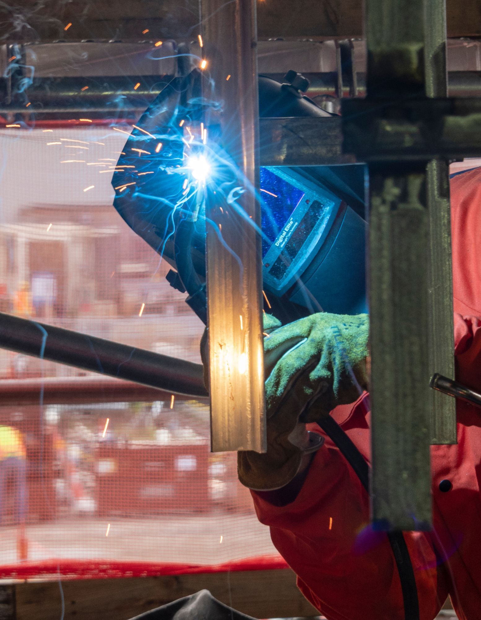 Person wearing a safety helmet and gloves welding metal.