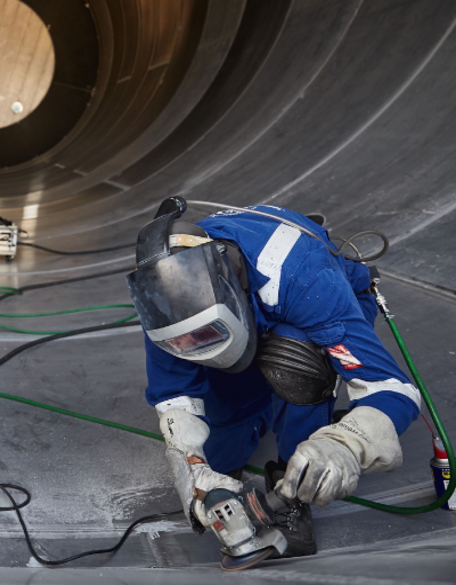 Person wearing a afety helmet and gloves  operatiing a power tool.