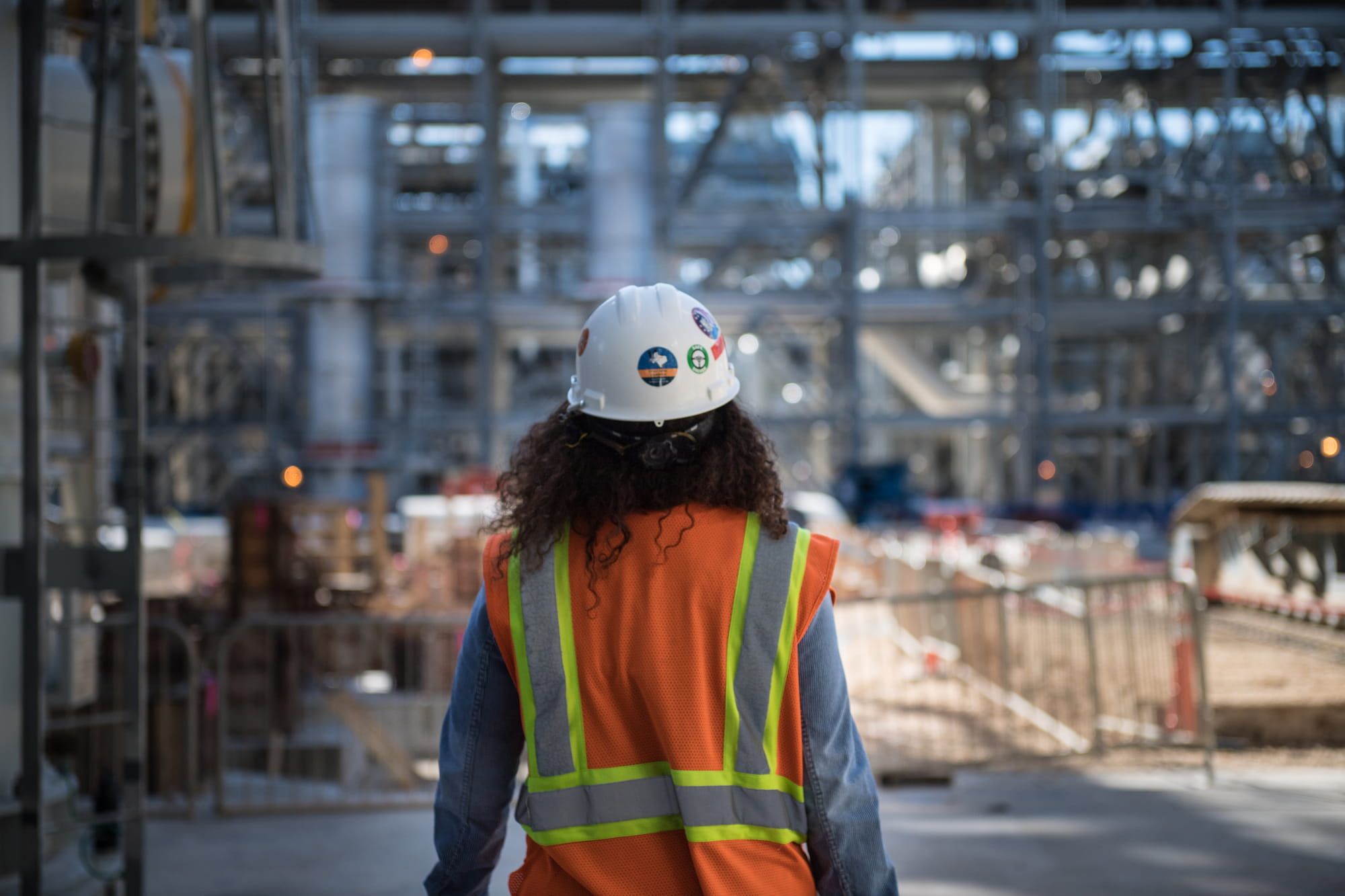 Person in a hard hat and safety vest on project site.