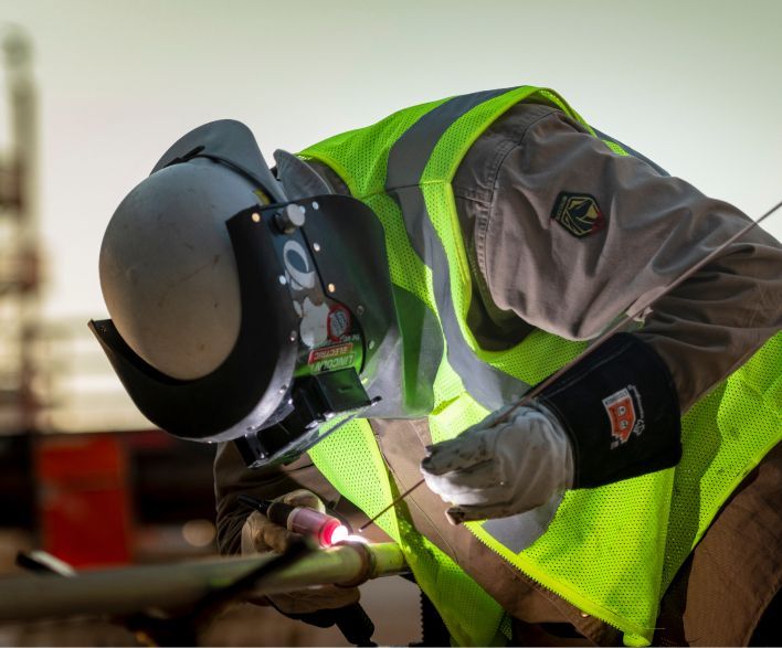 Person wearing safety gear welding a pipe.