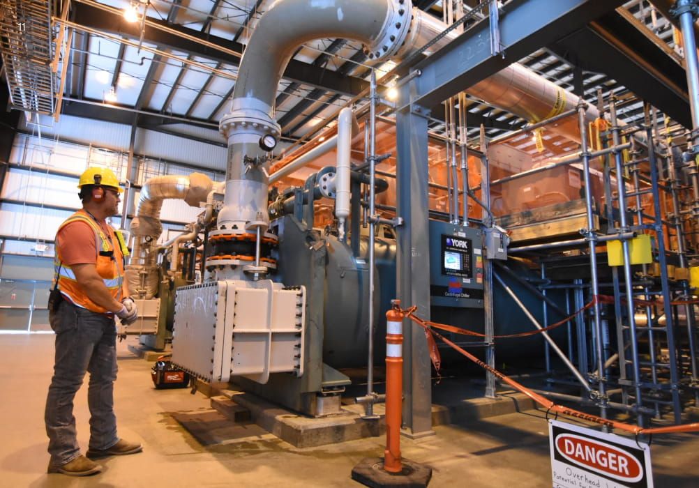 Person wearing safety gear inspecting machinery at the Hanford Waste Treatment facility.