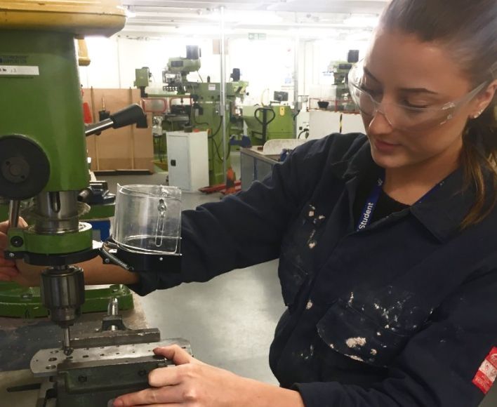 Young woman wearing safety goggles and operating machinery at the Institution of Engineering and Technology.