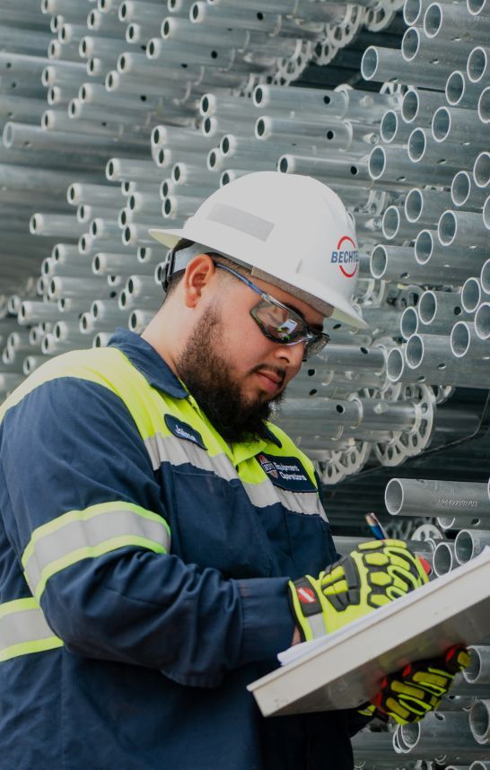 Bechtel team member in safety gear writing on a clipboard.