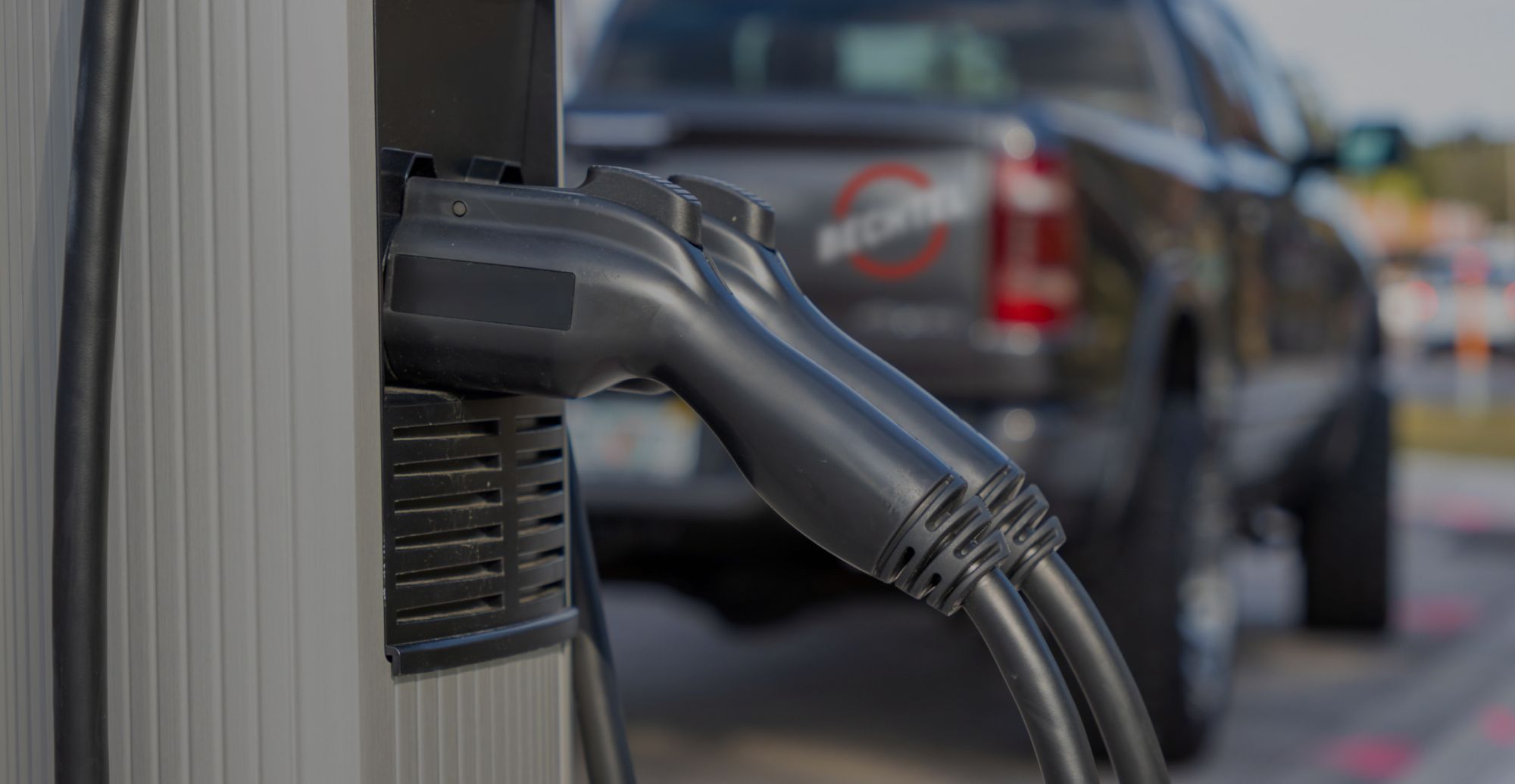 Two connectors plugged into electric vehicle charging station.