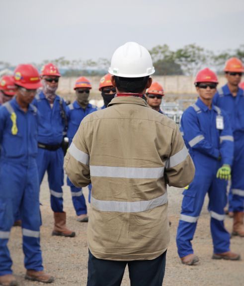 Group of people in safety gear getting briefed on site at Sabine Pass.