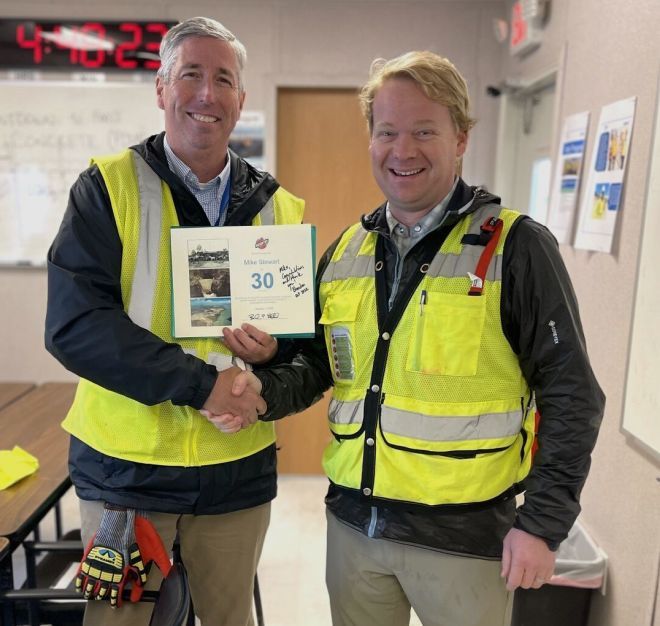 Bechtel CEO Brendan Bechtel recognizing employee Mike Stewart for 30 years of service at Bechtel with a signed certificate and handshake.