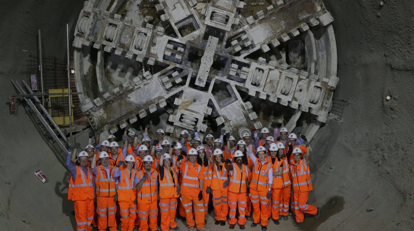 A group of people wearing safety gear in front of a large piece of equipment on the Elizabeth Line project site.