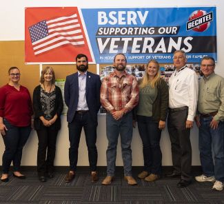 Bechtel BSERV members in front of a Bechtel-branded 'Supporting Our Veterans' sign.