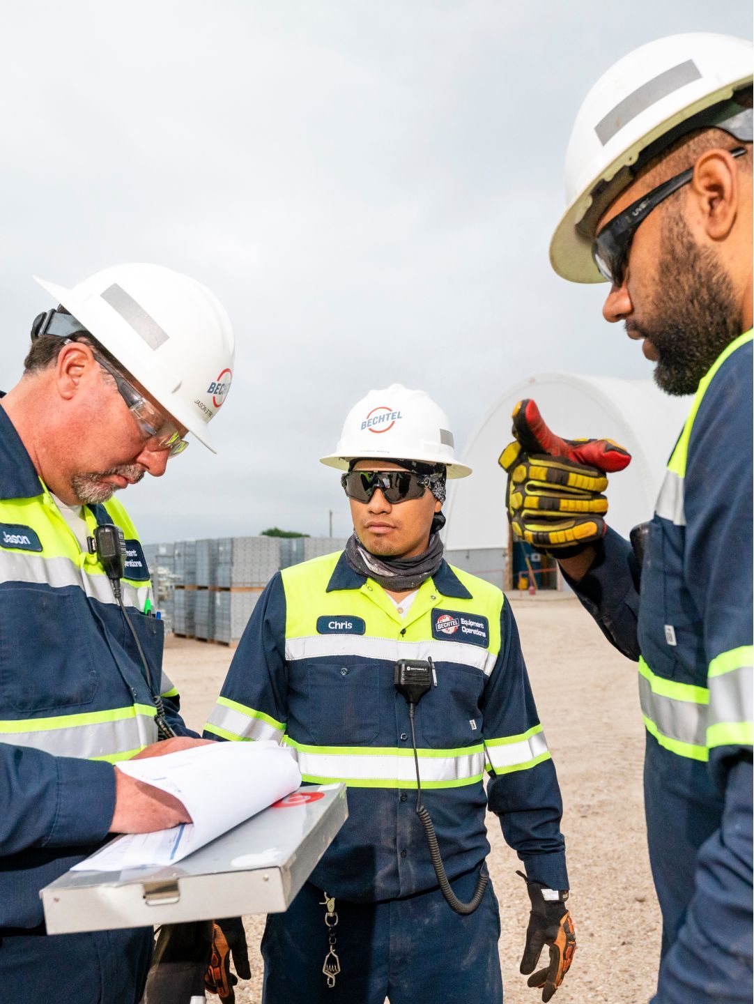 Three Bechtel Equipment Operations team members wearing safety gear in conversation.