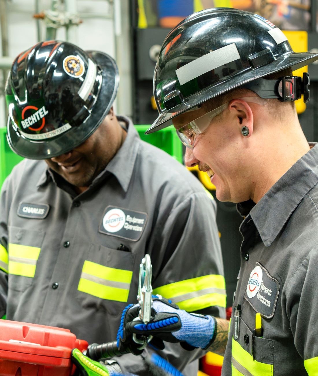 Two people wearing uniforms and Bechtel hard hats working together.