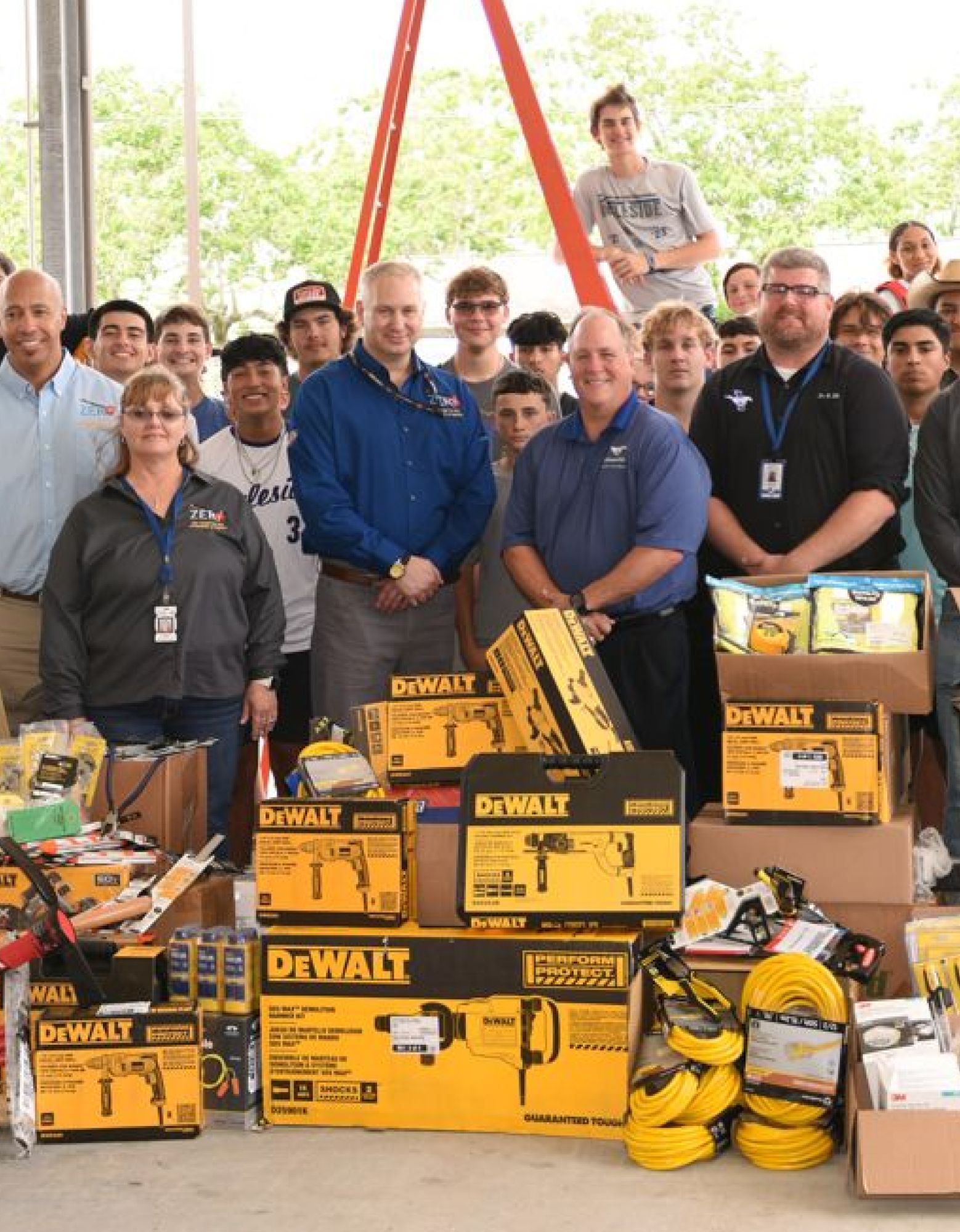Group of adults and high school students with a large pile of donated tools.