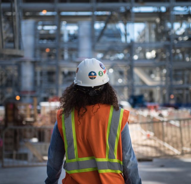Person in a hard hat and safety vest on project site.