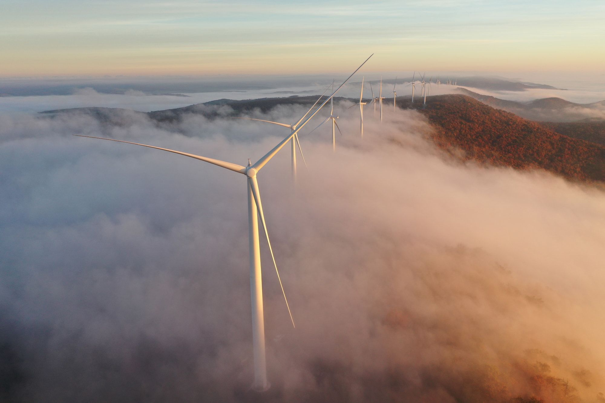 Wind turbines in a mountain range partially covered in clouds.