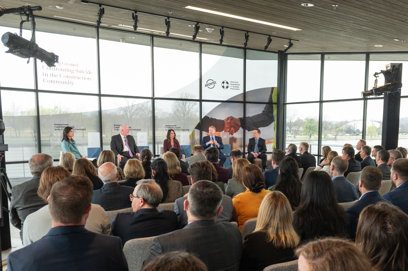 Bechtel executives making an announcement in the office of the American Society for Suicide Prevention in front of a window.