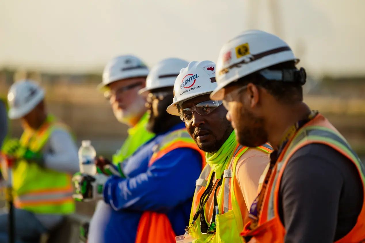 A diverse group of construction workers standing around in a circle