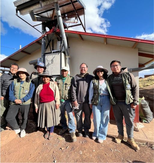 A group of people, including locals, in the Peruvian Andes mountains in front of a home.