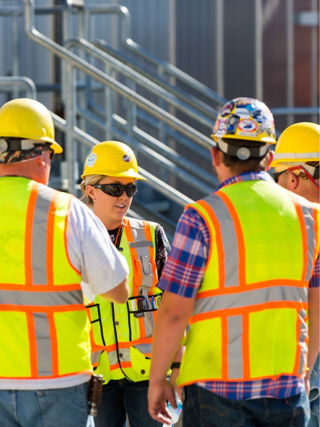 Group of people wearing safety vests and hard hats.