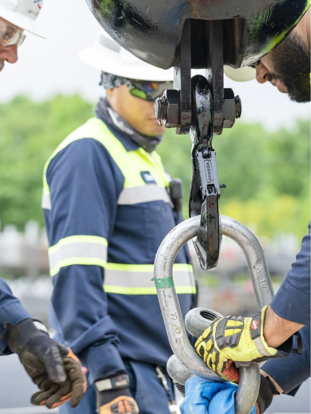 Three people in safety gear working together on a project.